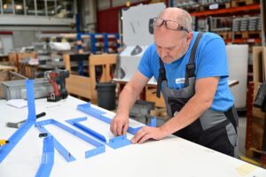 Mitarbeiter der Montage am Montieren von blauen Blechteilen.